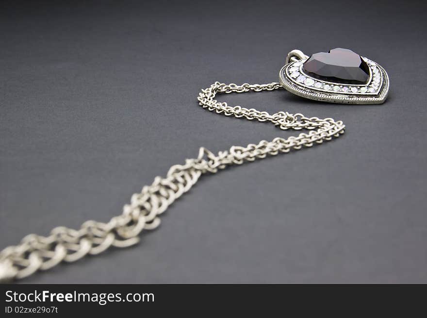 Silver necklace with heart-shaped pendant on a black background