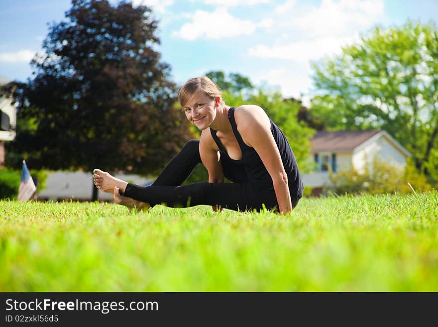 Young girl doing yoga exercise alone on the lawn