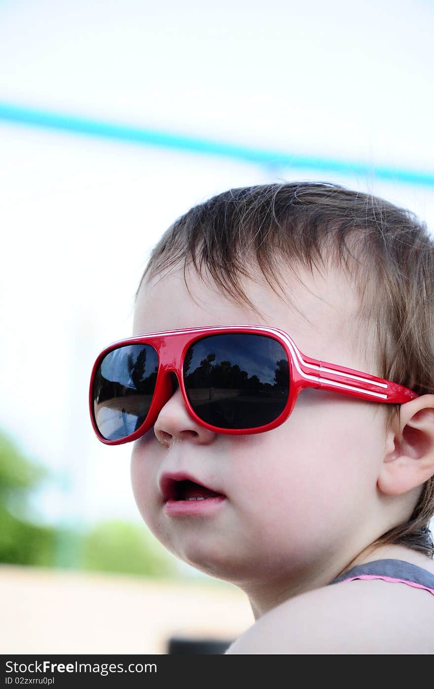 Little girl outside wearing red sunglasses. Little girl outside wearing red sunglasses