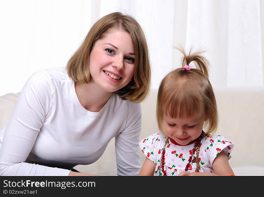 Young mother and her baby daughter spending time together. Dress up in costume jewelry.