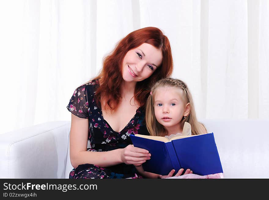 The little girl and her mother read a book together on the couch