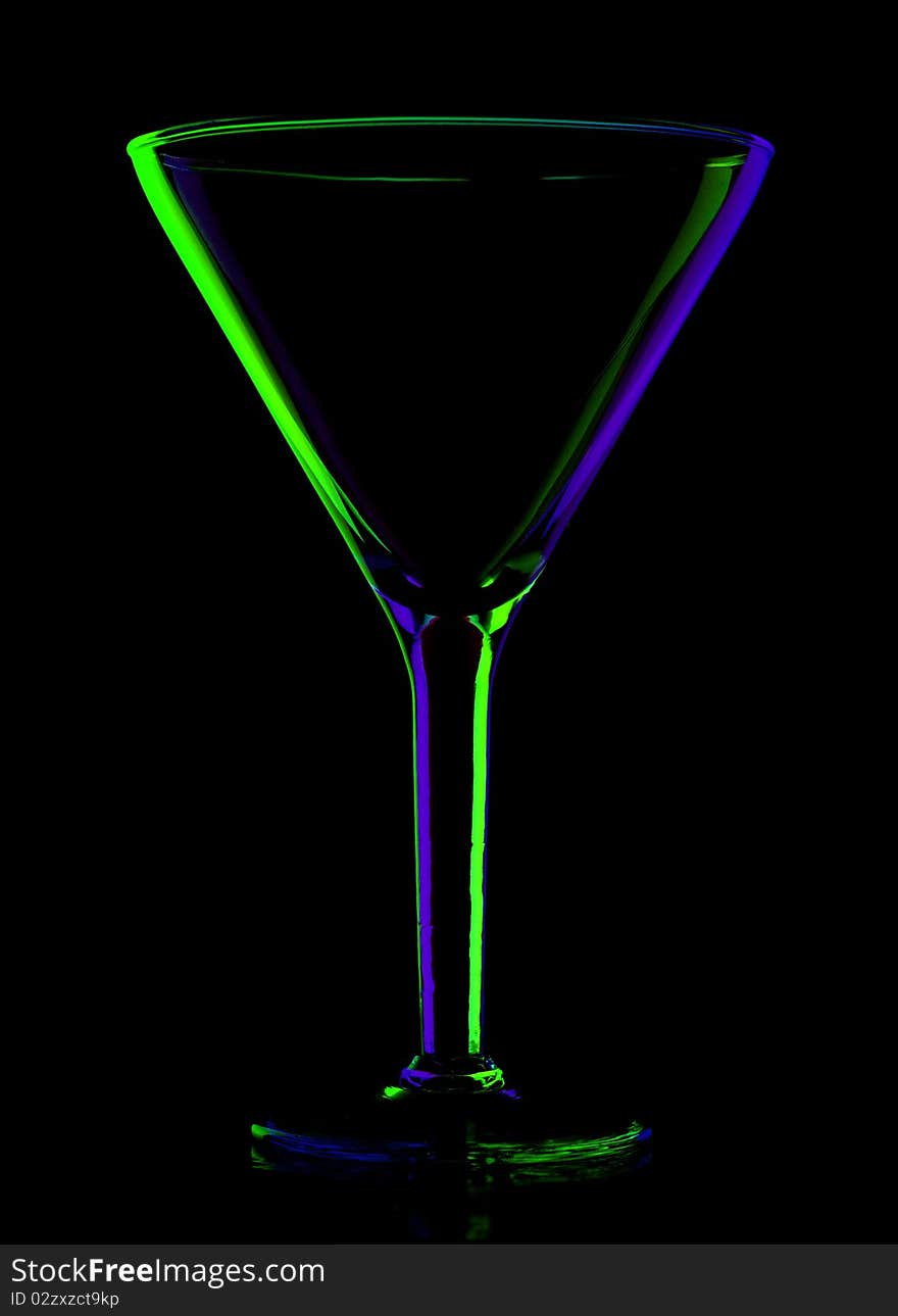 Transparent colored empty martini glass on black