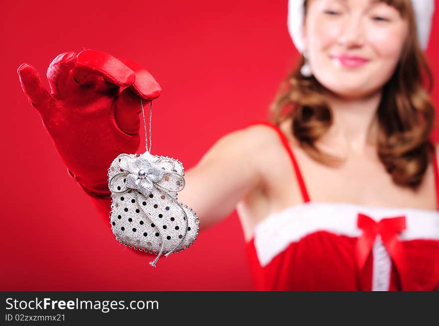 Portrait of a young girl dressed as Santa Claus on a red background. Girl gives gifts. Happy New Year and Merry Christmas!