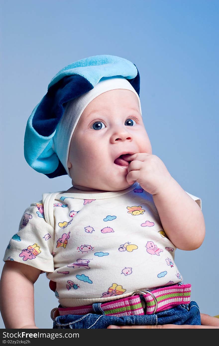 Amusing baby boy in a beret in a studio on a dark blue background