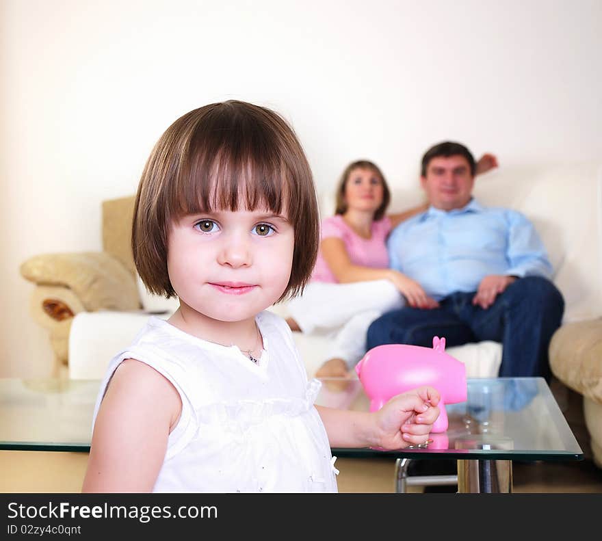 A little girl hides her money in the pig piggy bank.