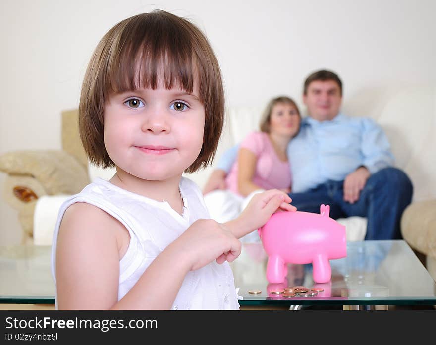 A little girl hides her money in the pig piggy bank.