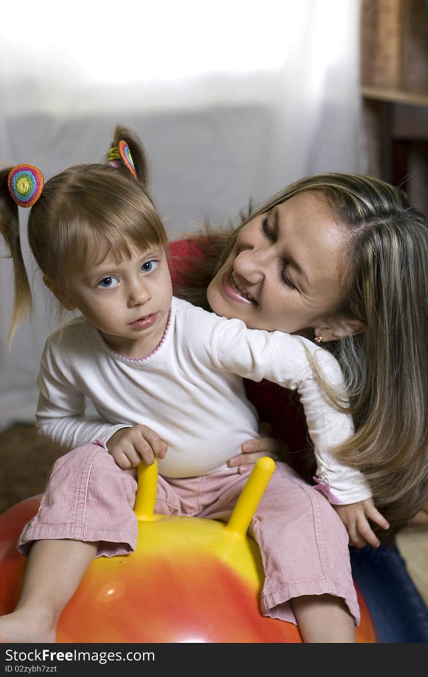 Happy mother and daughter playing with a ball