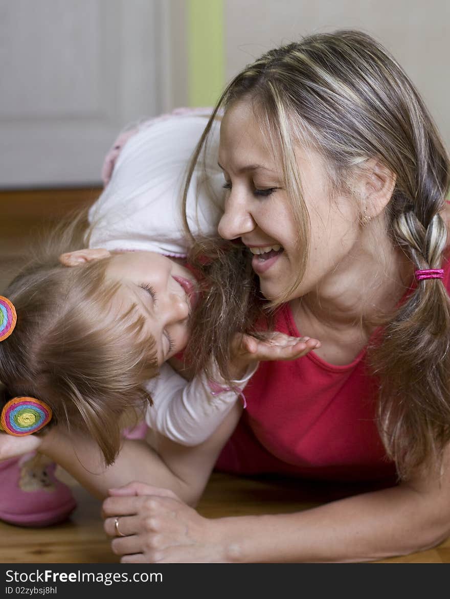 Happy mom plays with her daughter at home