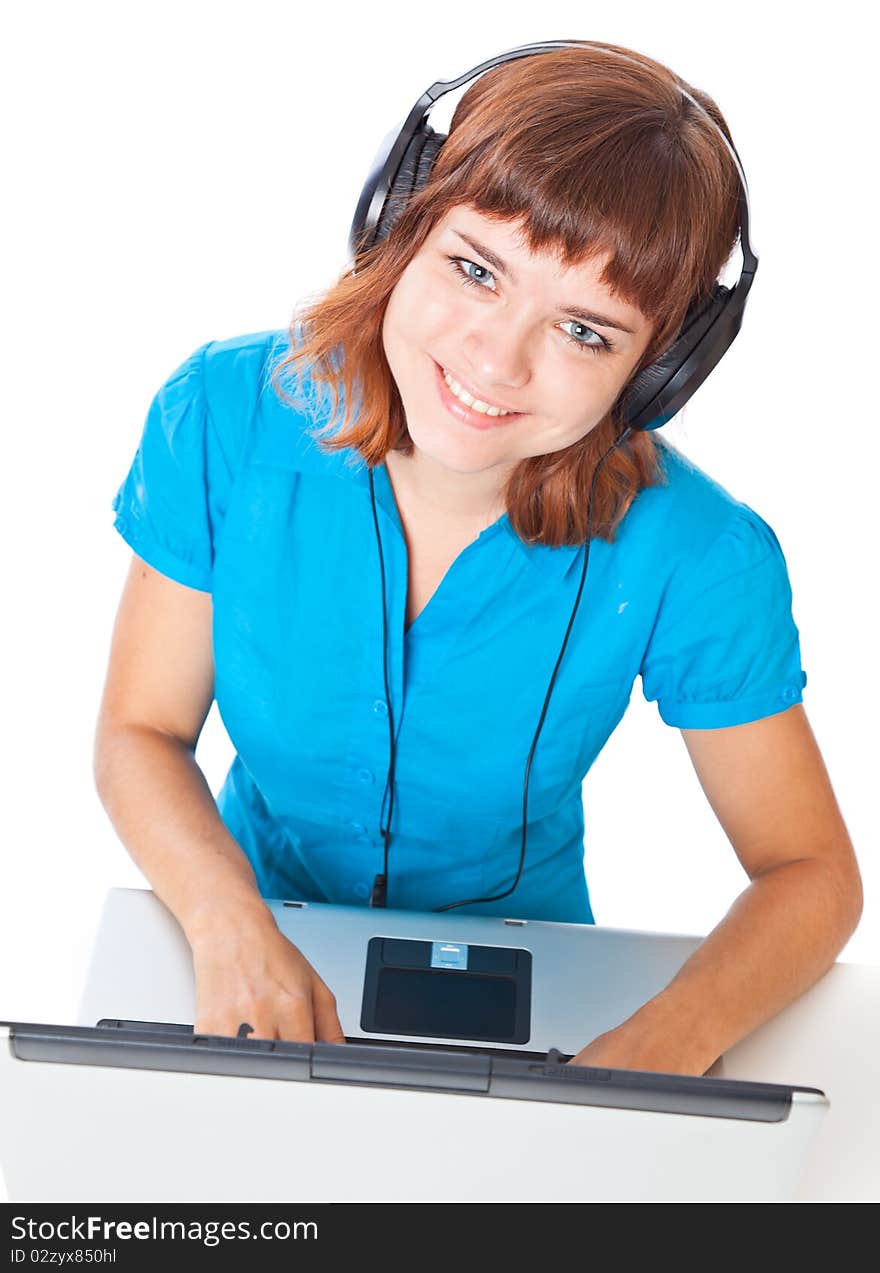 Red-haired teen-girl listen to music in headphones with laptop. Isolated on white background