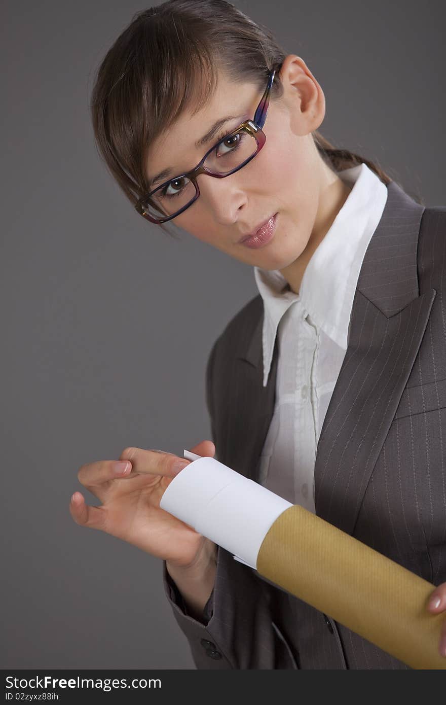 Portrait of business woman holding blueprints over grey background. Portrait of business woman holding blueprints over grey background