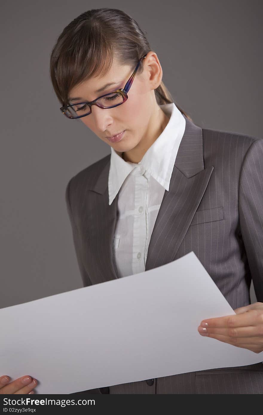 Portrait of business woman holding white paper over grey background. Portrait of business woman holding white paper over grey background