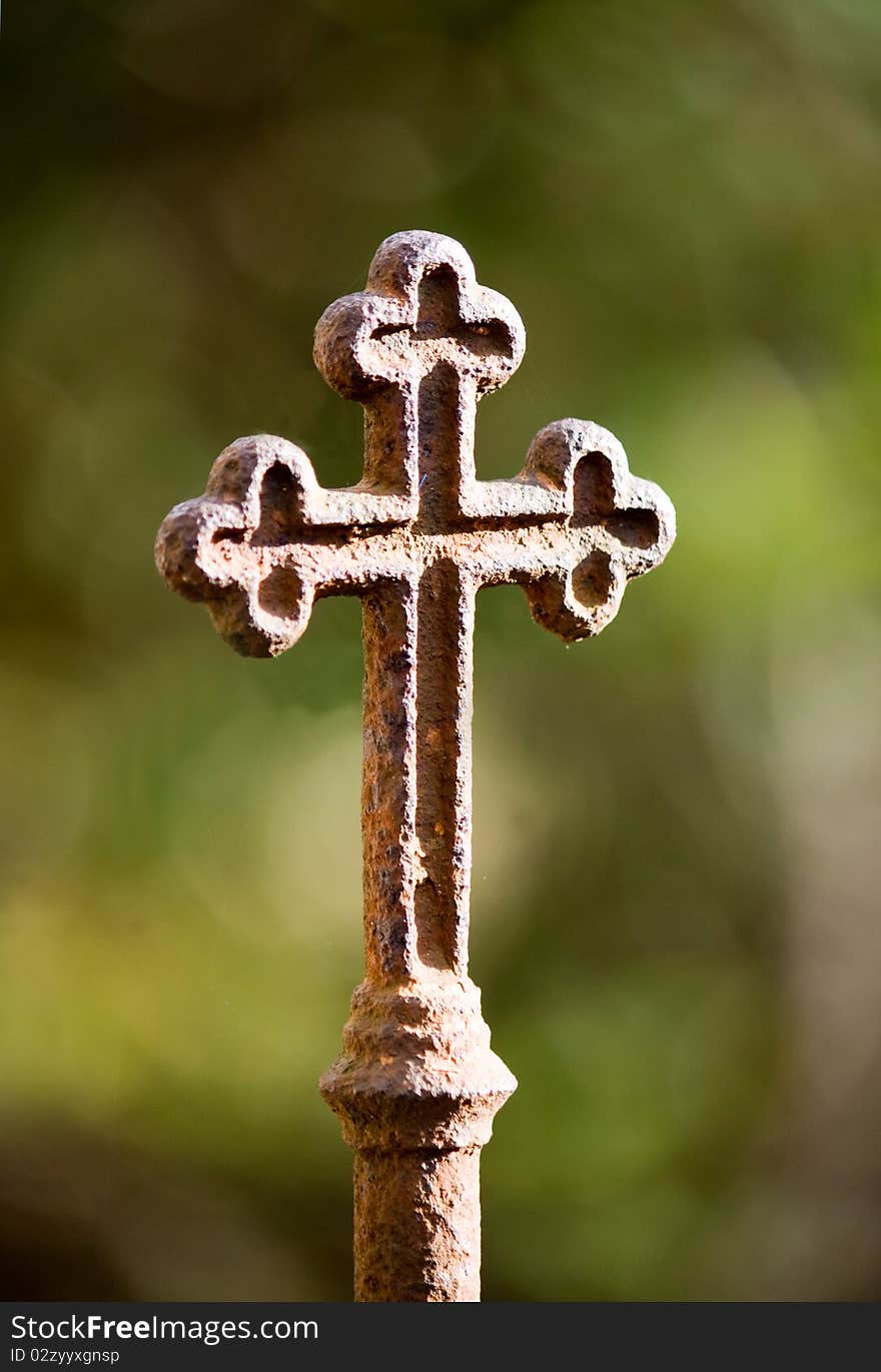 Rusty cross against green background