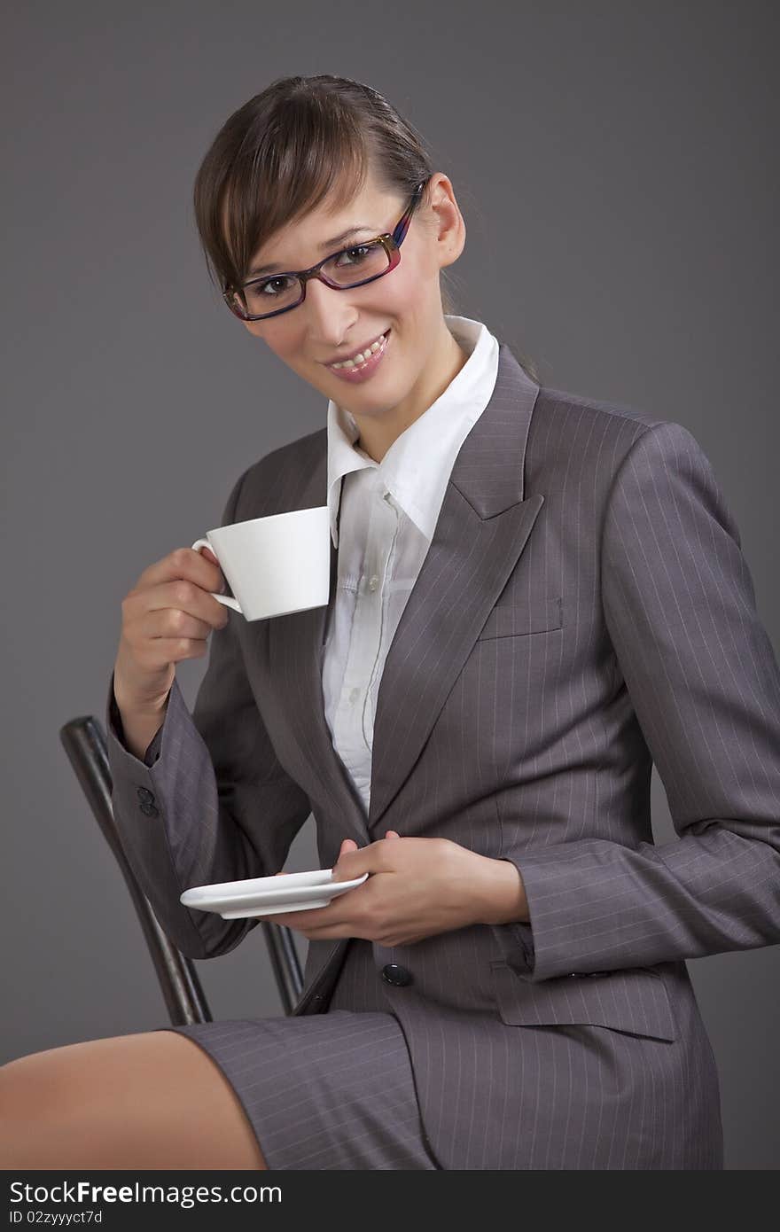 Business woman drinking tea over grey background