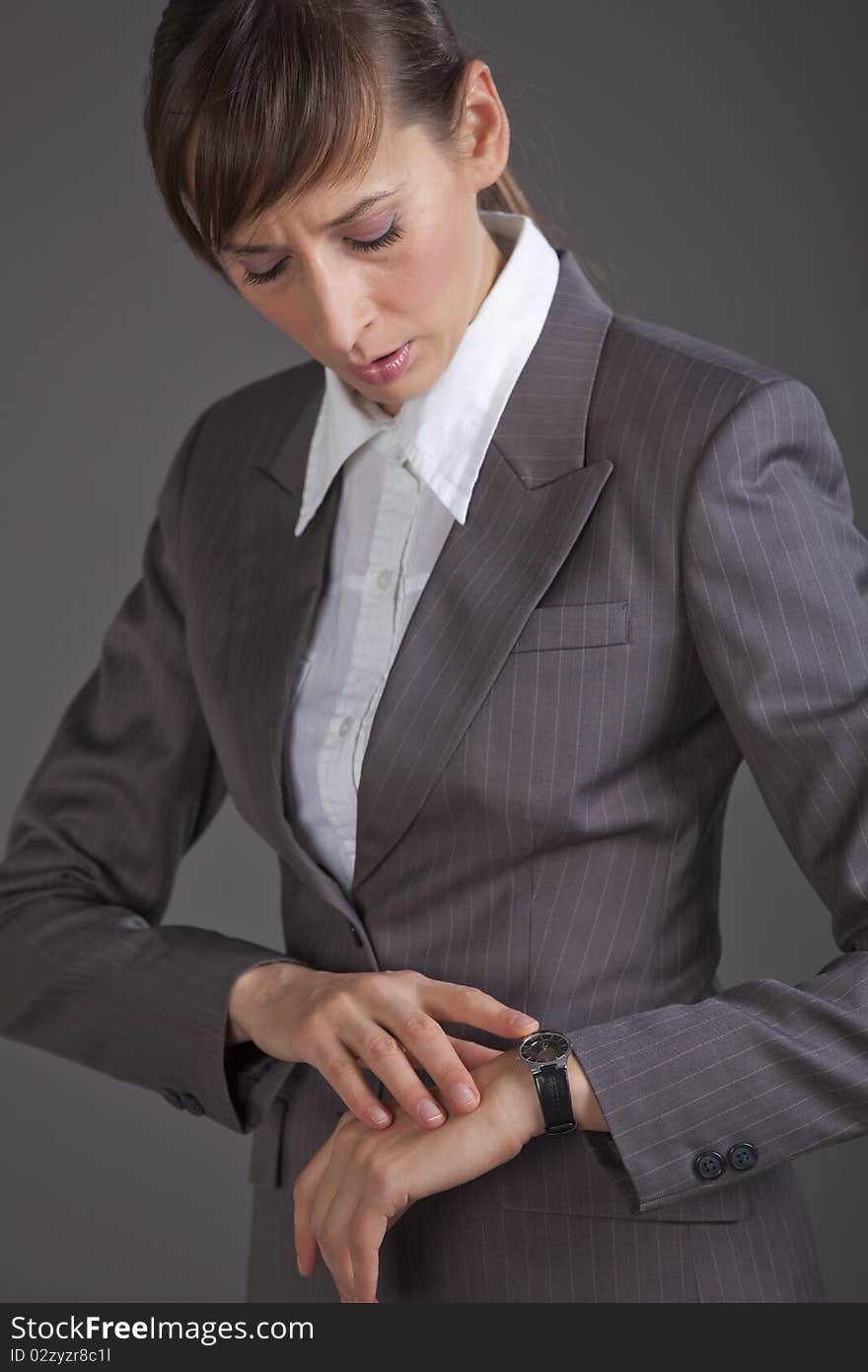 Business woman looking at her watch over grey background