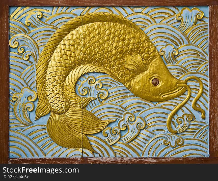 Fish carve gold paint in temple wall