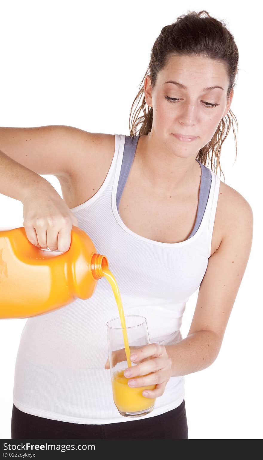 A woman in fitness attire is pouring a glass of orange juice. A woman in fitness attire is pouring a glass of orange juice.