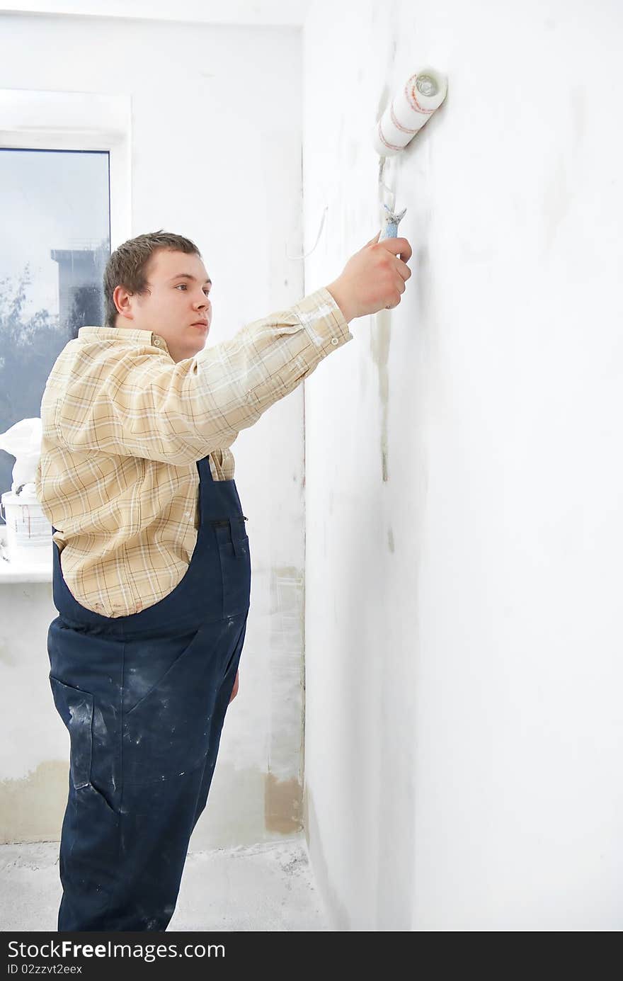 Worker painting wall with roller