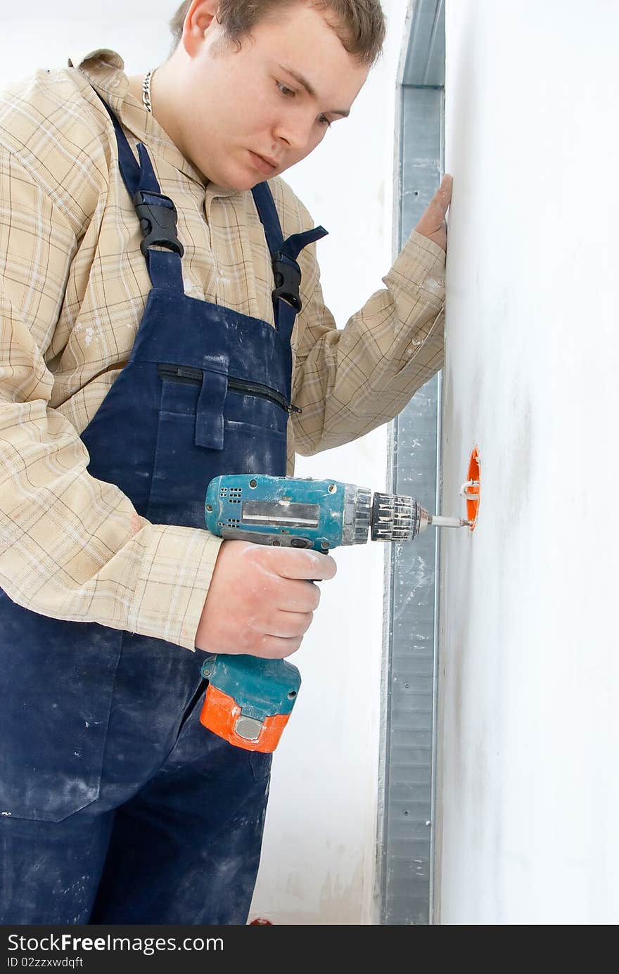 Young man drill a wall for installing power socket. Young man drill a wall for installing power socket