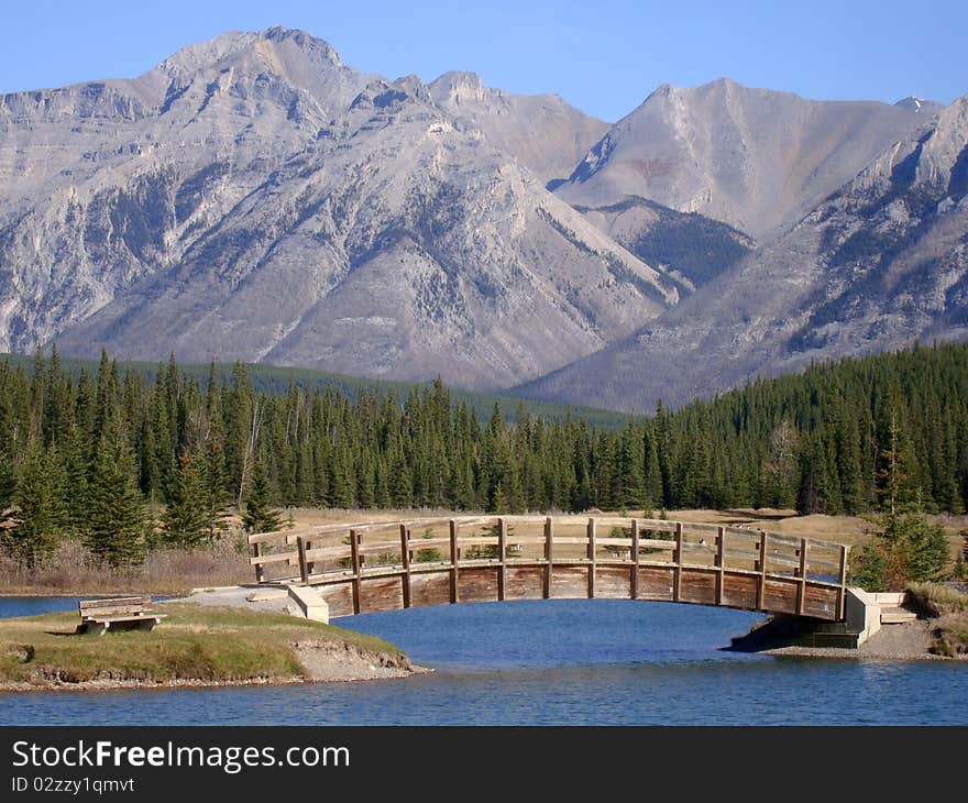 Wooden bridge crossing the lake on the way to the mountain hiking trails. Wooden bridge crossing the lake on the way to the mountain hiking trails.