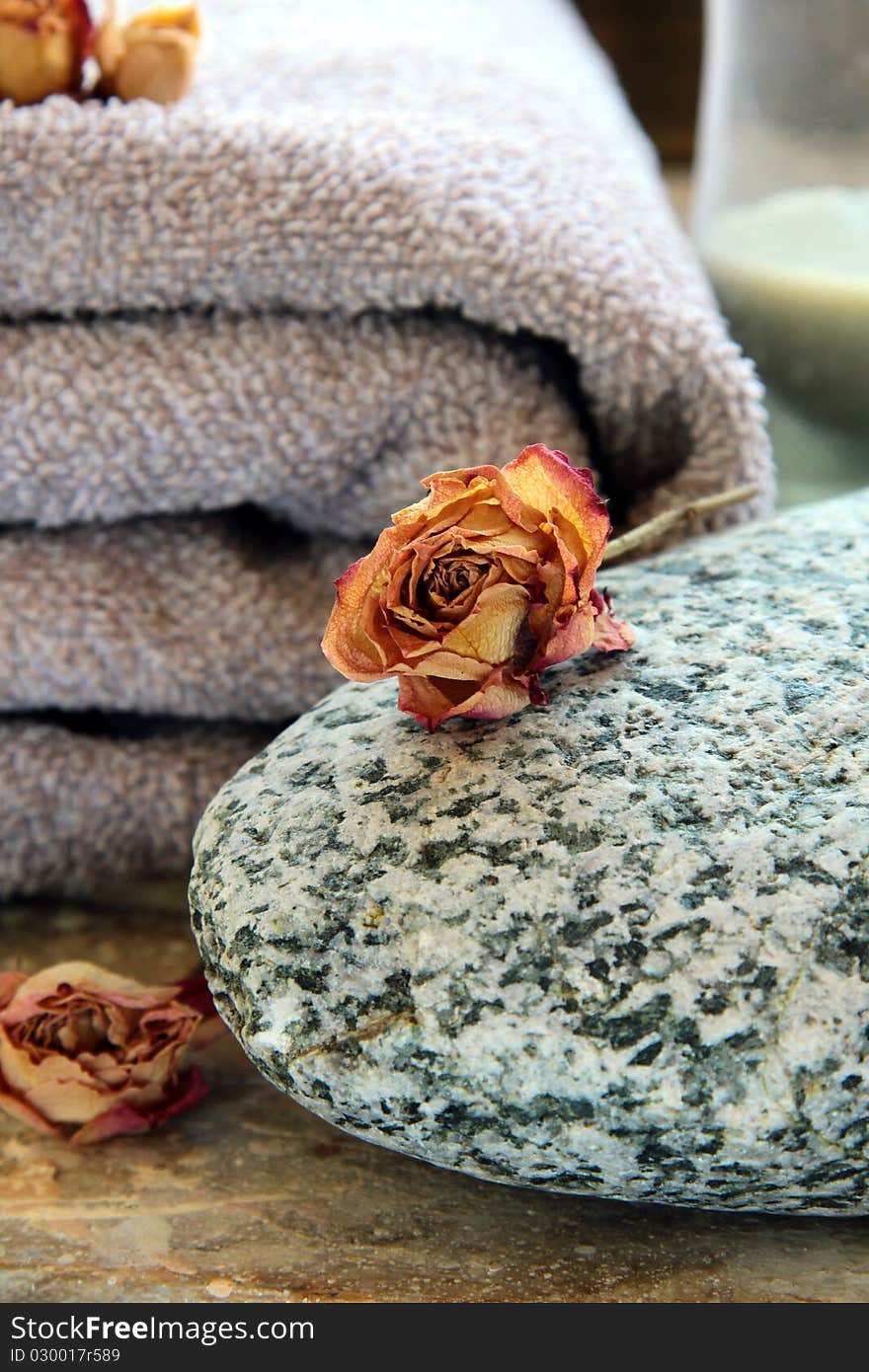 Gray towel with a rock and a candle and dry roses