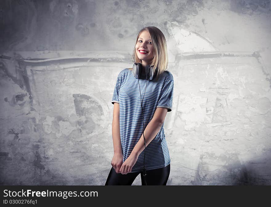 Smiling beautiful woman wearing headphones with graffiti on the background. Smiling beautiful woman wearing headphones with graffiti on the background