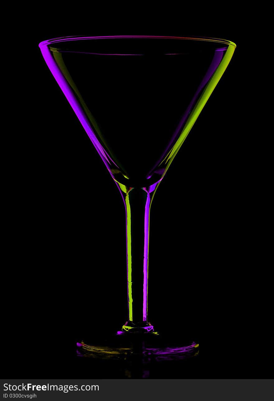 Transparent colored empty martini glass on black