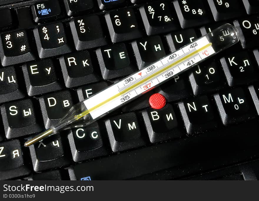 Mercury thermometer lying on computer keyboard. Mercury thermometer lying on computer keyboard