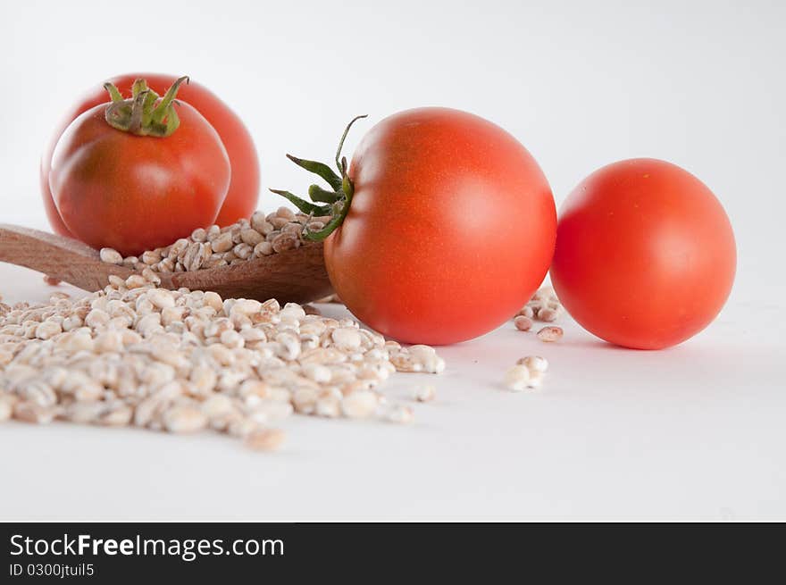 Grain and tomatoes spilled over a wooden spoon