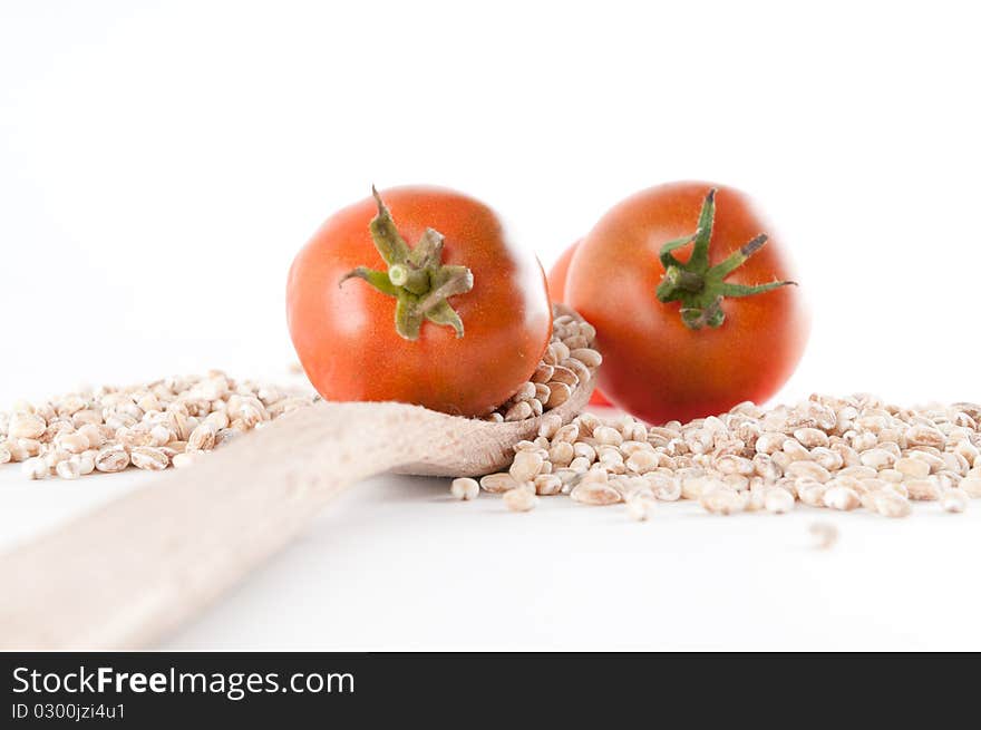 Grain and tomatoes spilled over a wooden spoon