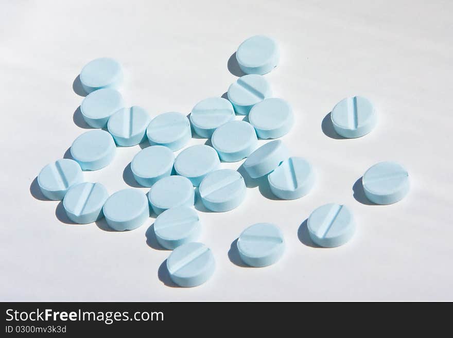 Some small blue  pills on white background. Some small blue  pills on white background