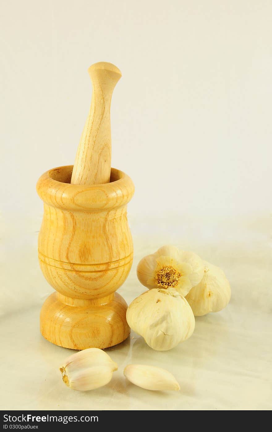 A wooden muller and garlics on white