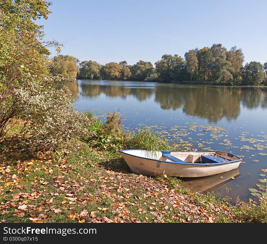 Boat on pond bank in park. Autumn season