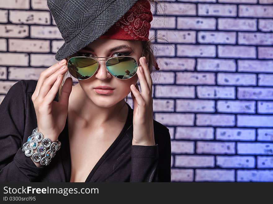 Trendy girl teenager posing  against a brick wall.