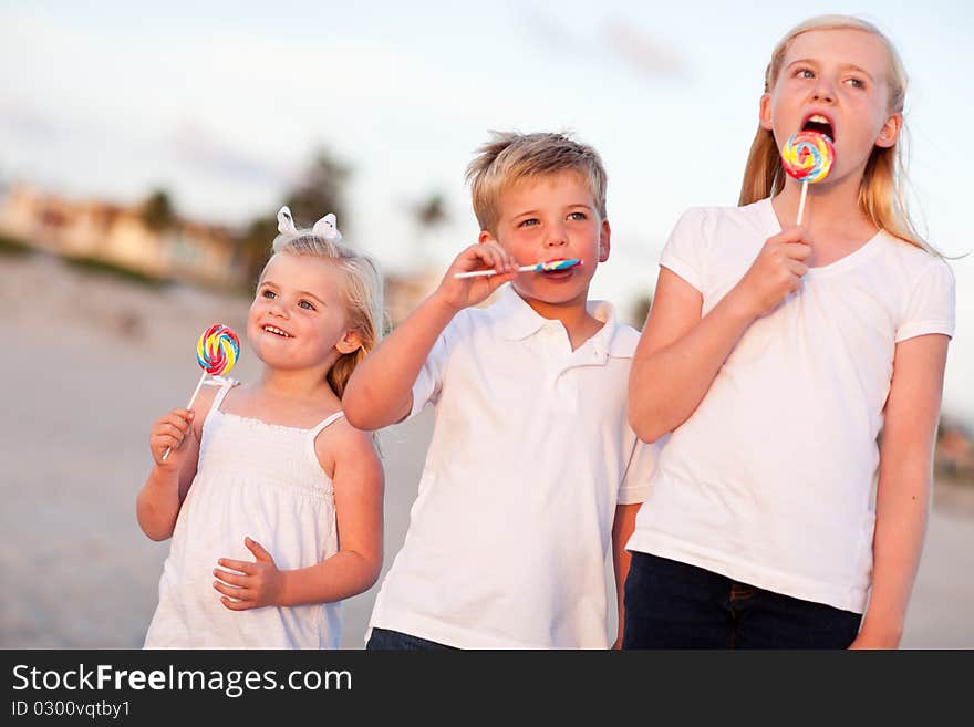 Cute Brother and Sisters Enjoying Their Lollipops at the Beach. Cute Brother and Sisters Enjoying Their Lollipops at the Beach.