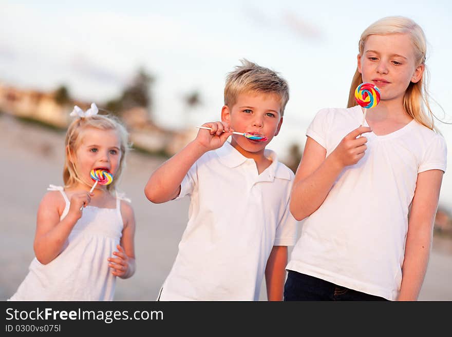 Cute Brother and Sisters Enjoying Their Lollipops at the Beach.