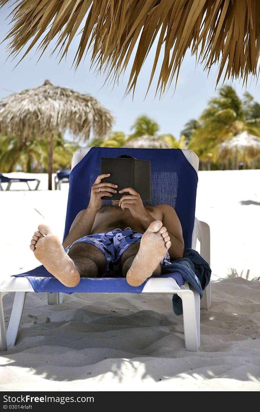 Man on the beach reads a book