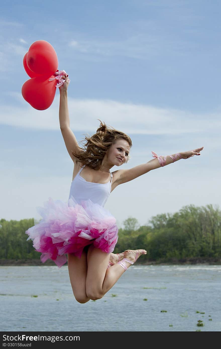 Young beautiful woman jumping with balloons.