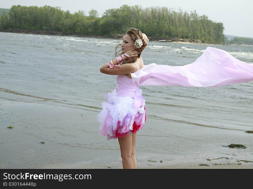 Young woman with pink fabric fluttering in the win