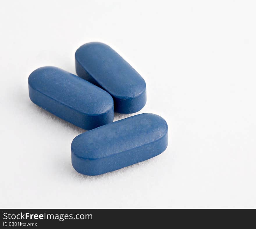 Macro shot of Three blue tablets on white. Macro shot of Three blue tablets on white