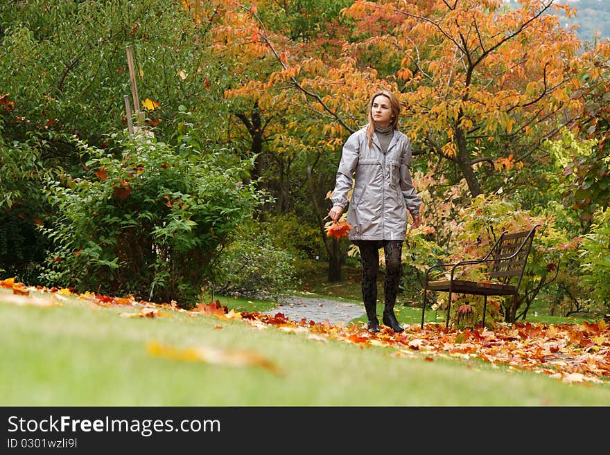 Beautiful girl goes on lane autumn park