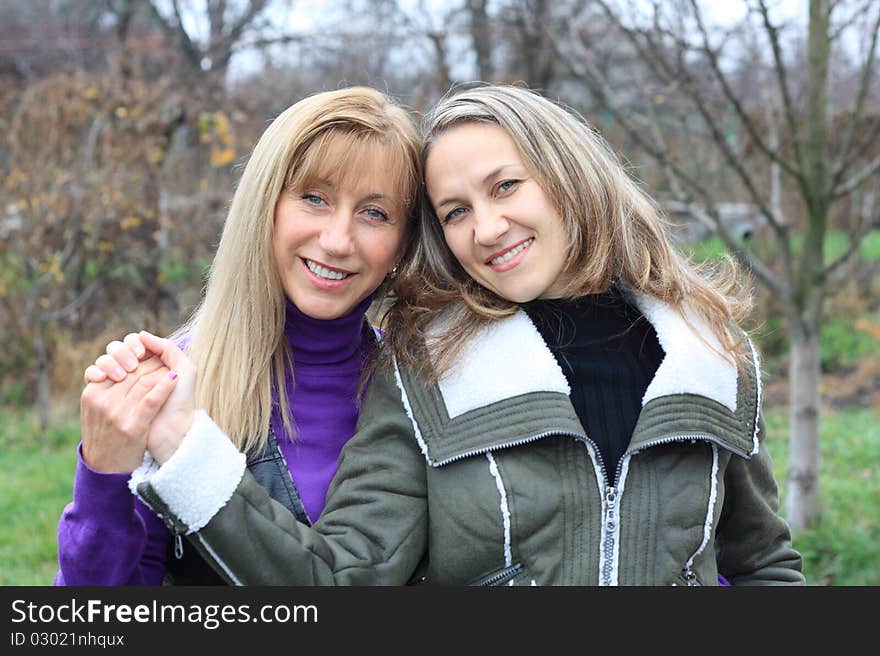 Two women outdoors embracing and smiling. Two women outdoors embracing and smiling