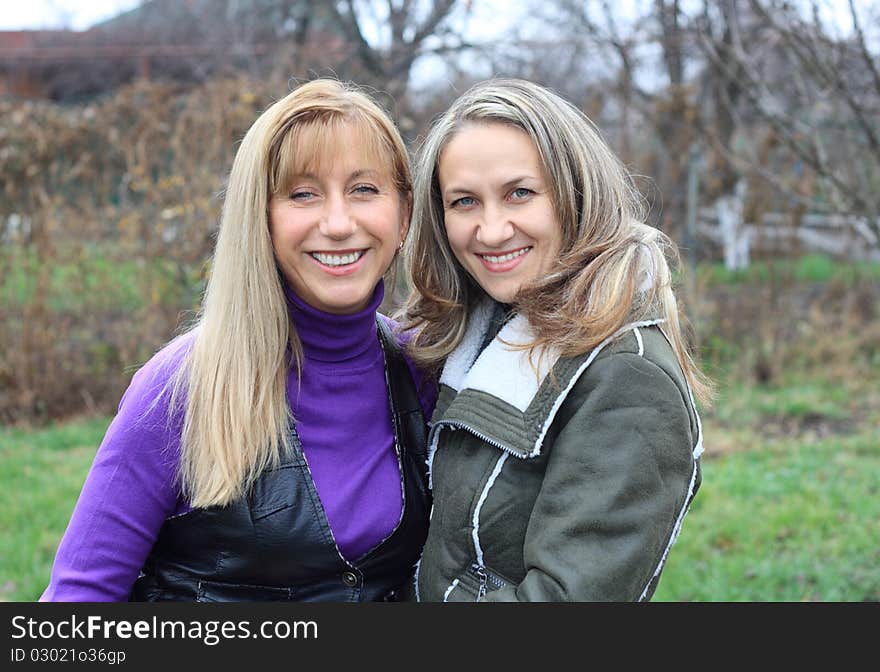 Two women outdoors embracing and smiling. Two women outdoors embracing and smiling