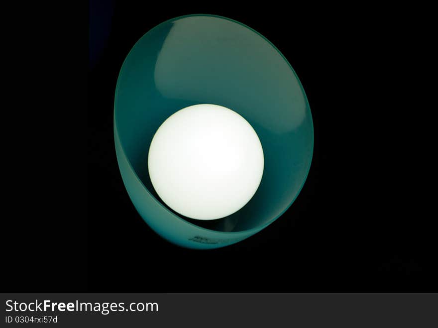 A single hooded florescent light on a dark background. A single hooded florescent light on a dark background.