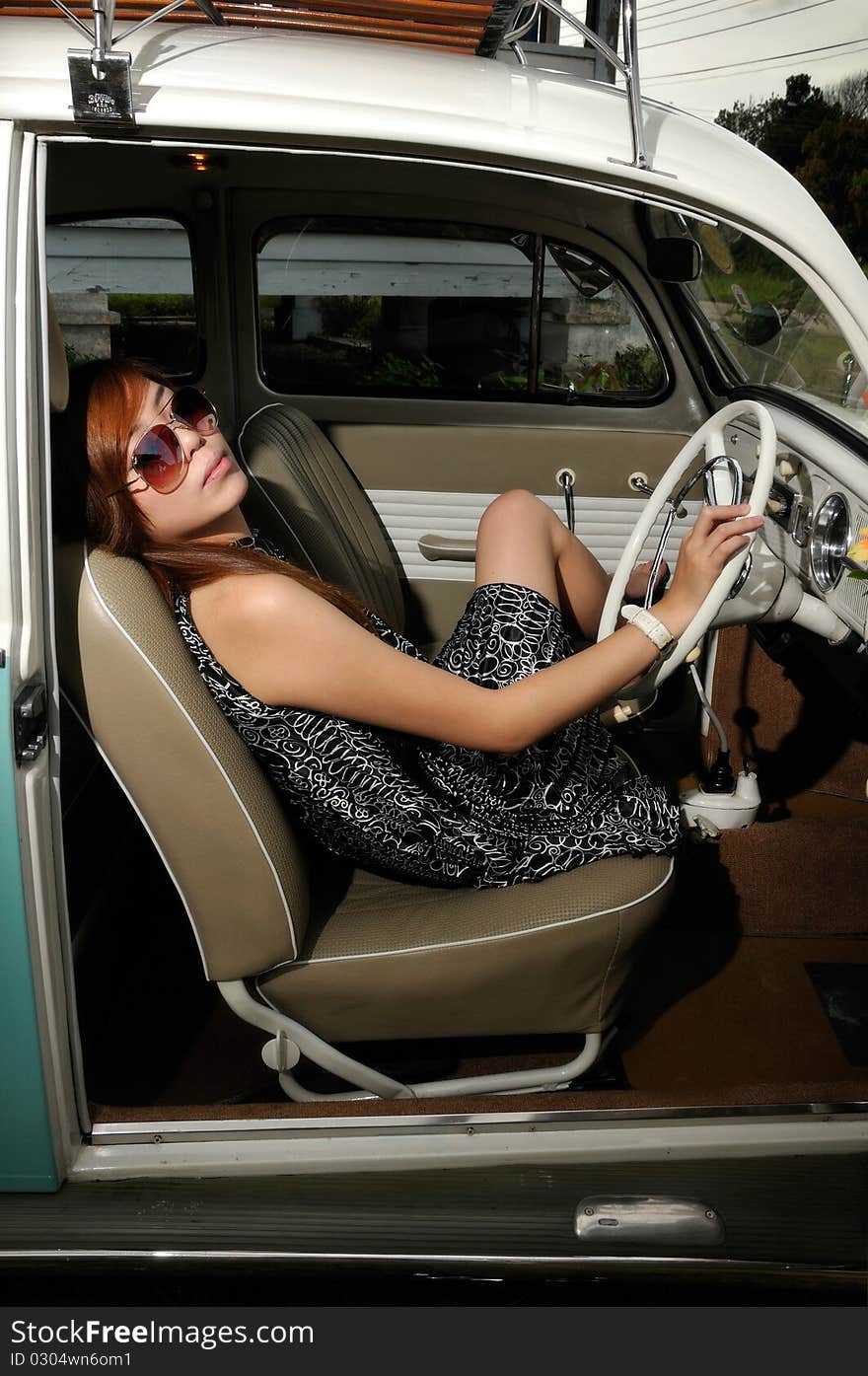 A girl sitting inside an antique car with sun glasses. A girl sitting inside an antique car with sun glasses