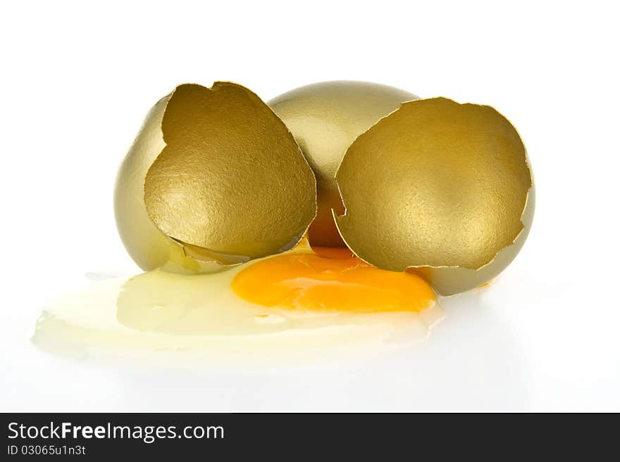 Broken gold egg on white background.