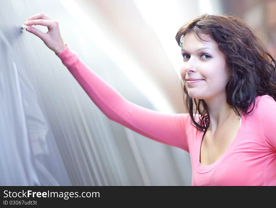 Pretty young college student writing on the chalkboard/blackboard during math class (shallow DOF; color toned image)