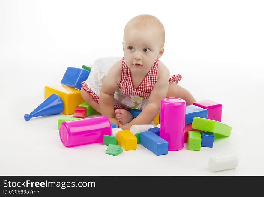 Girl plaies with plastic cubes, on white background.