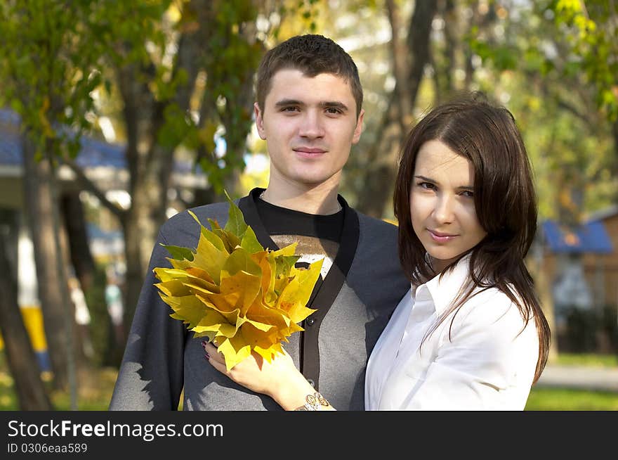 Young couple with autumn leas over defocused background. Young couple with autumn leas over defocused background