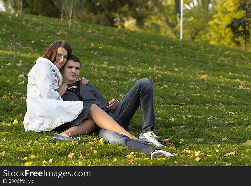 Young couple sitting in the autumn city park (defocused background). Young couple sitting in the autumn city park (defocused background)