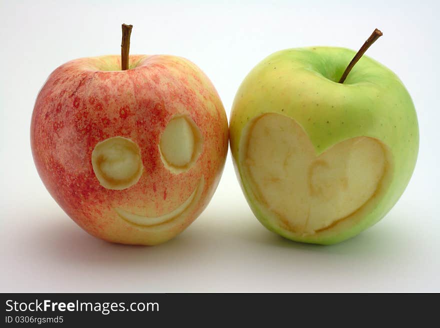 Two carved apples. One is a smiling face the other is a heart. Two carved apples. One is a smiling face the other is a heart